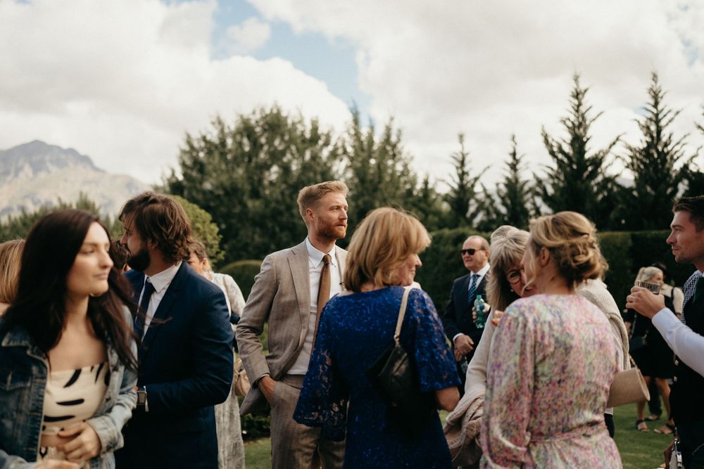 Wedding guests mingling outdoors with mountain scenery in the background.