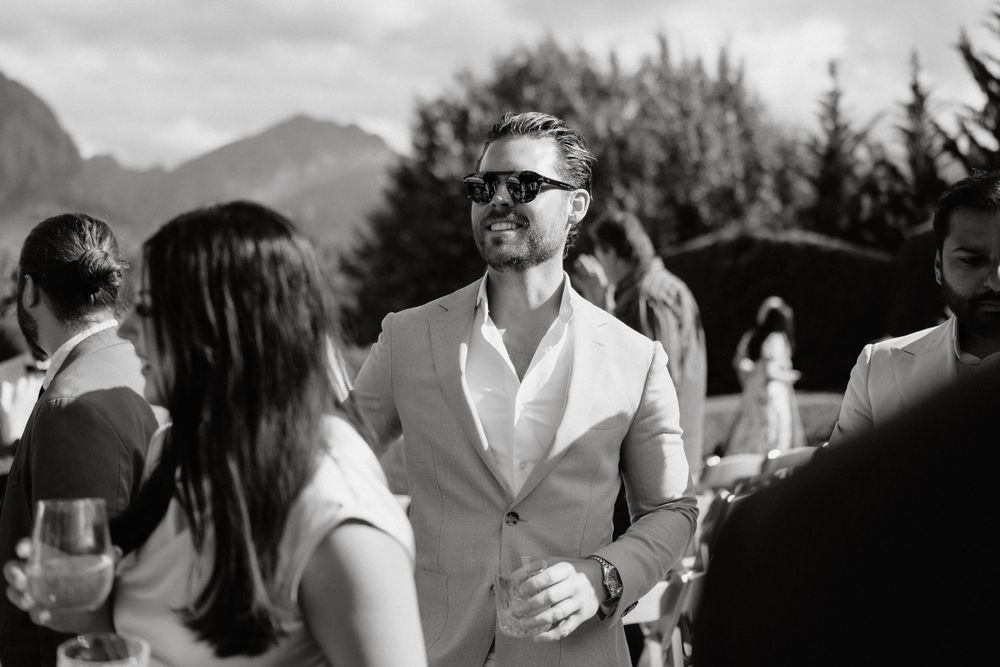Stylish guest in sunglasses mingles at outdoor mountain wedding reception.