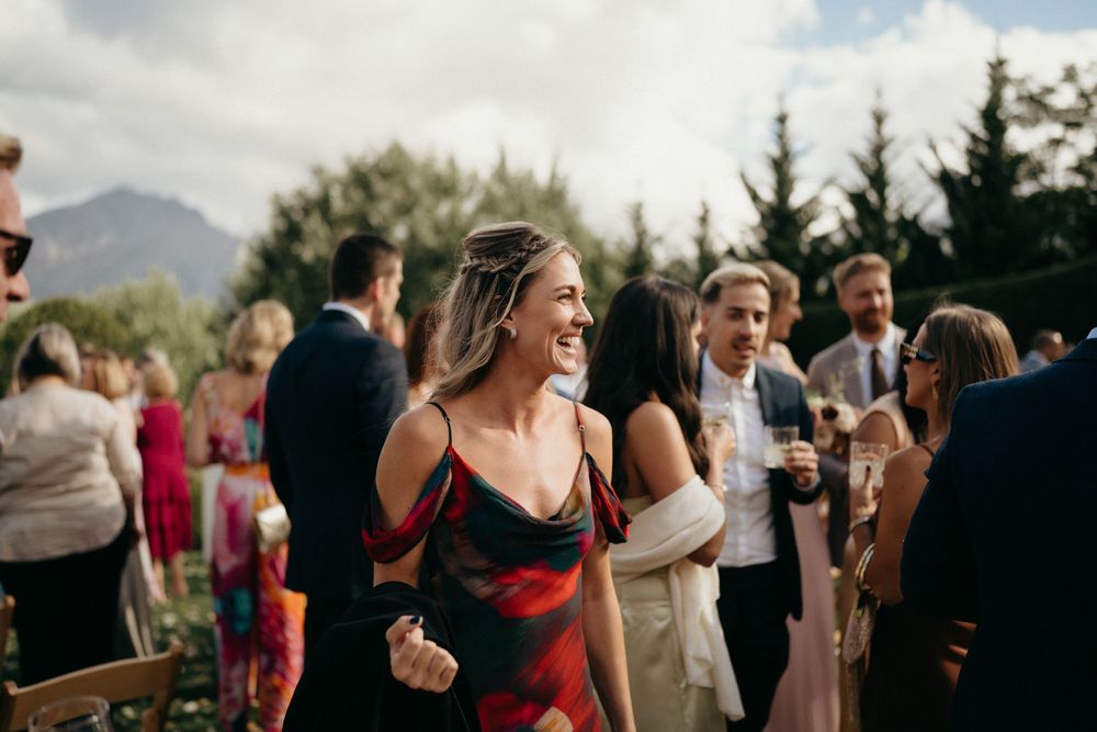Wedding guests enjoying a lively outdoor reception with mountains visible in the background.