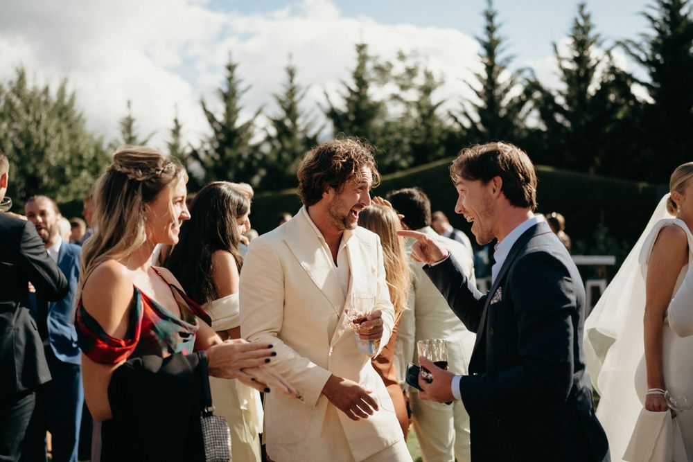 Outdoor wedding reception with guests socializing in sunny garden setting.
