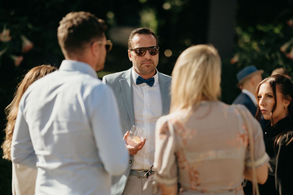 Wedding guests socializing during outdoor cocktail hour wearing formal attire.