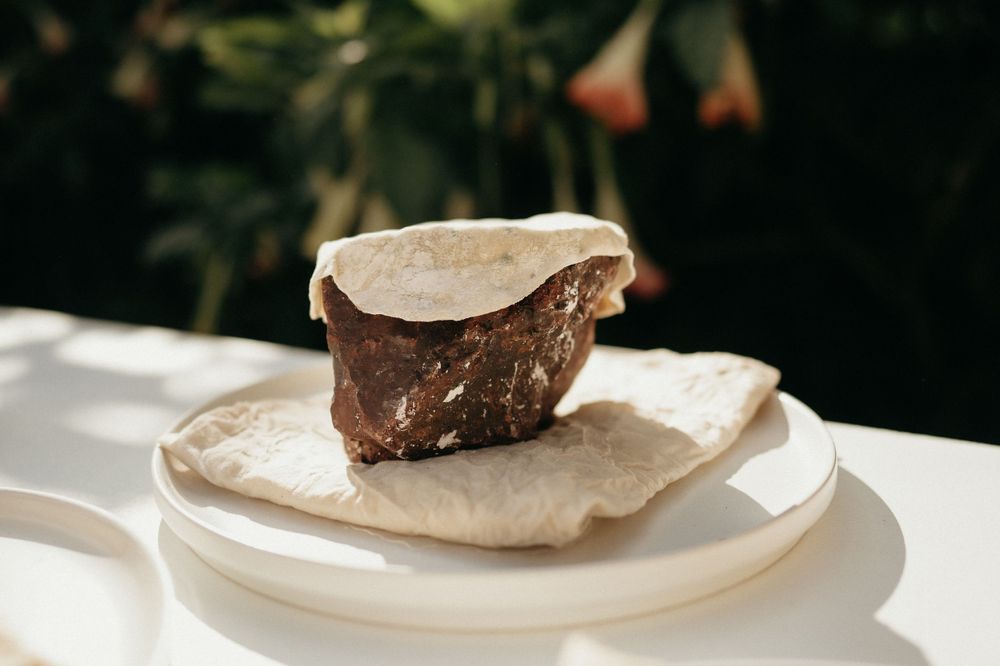 A chocolate dessert served on a white plate at an outdoor wedding reception.