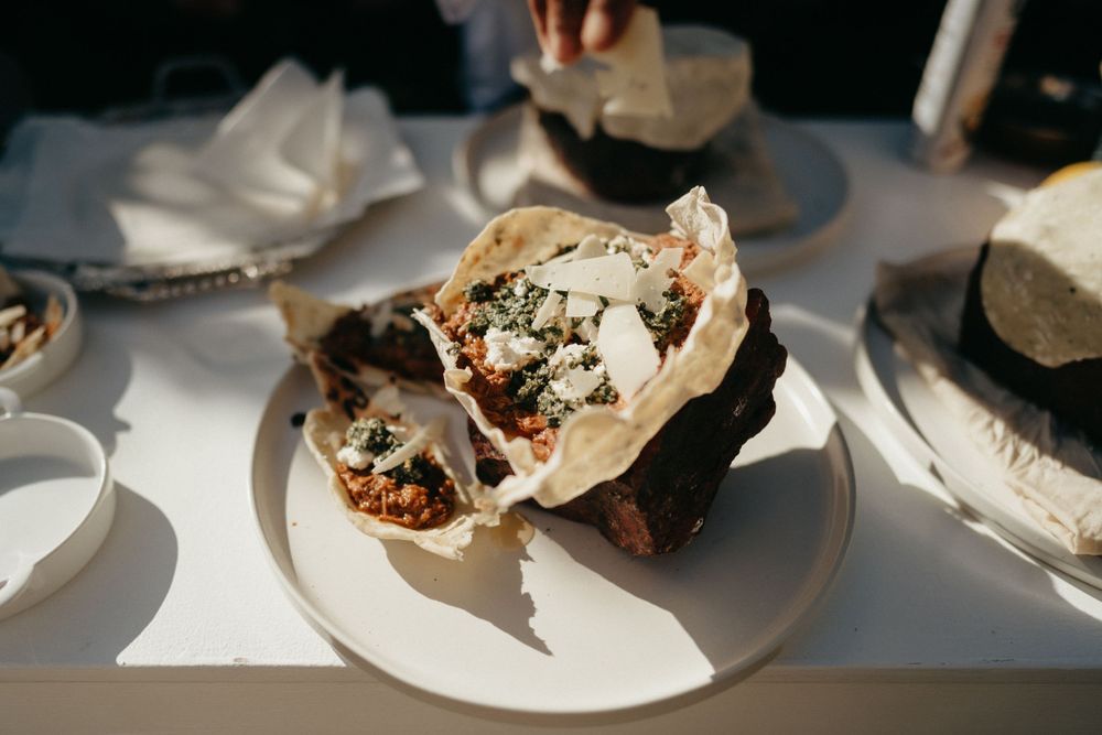 A white plate holds two wrapped burrito or sandwich items with fillings visible on a table setting.