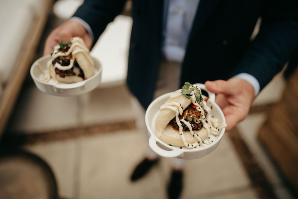 Close-up of hands serving elegant plated appetizers at wedding reception.