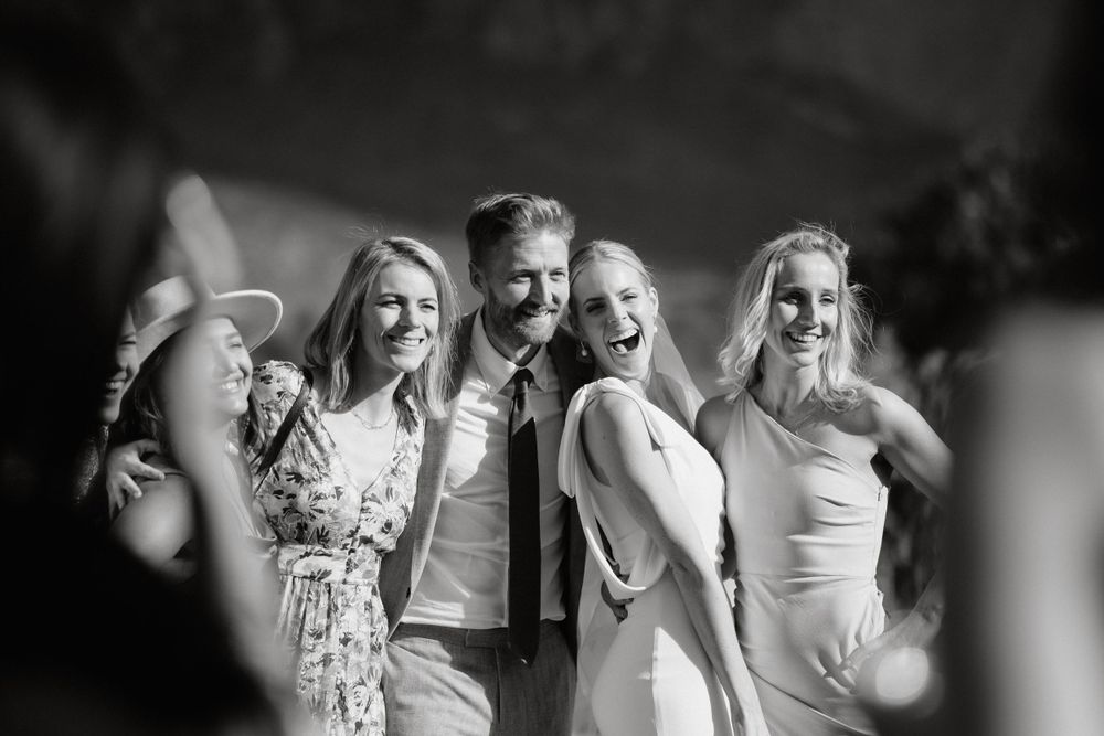 A group of wedding guests pose together for a candid black and white celebration photo.