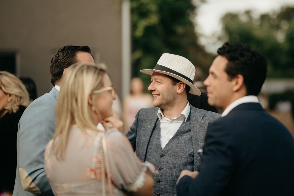 Wedding guests engaged in casual conversation outdoors.