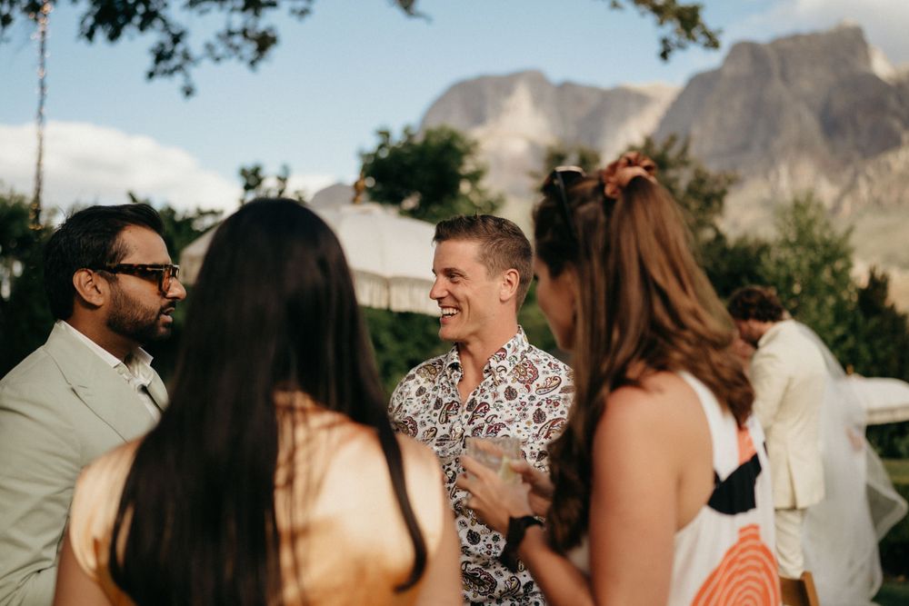 Group of guests mingling at an outdoor event with mountain scenery in the background.