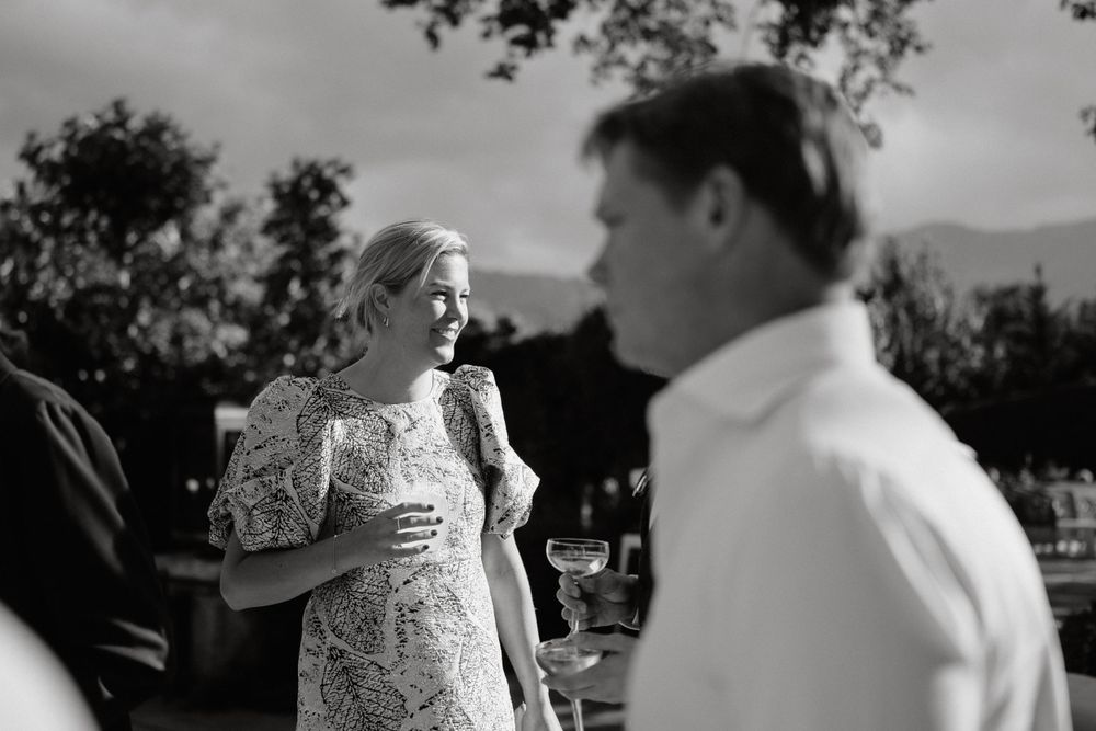 A black and white candid photograph capturing a festive outdoor wedding celebration moment.