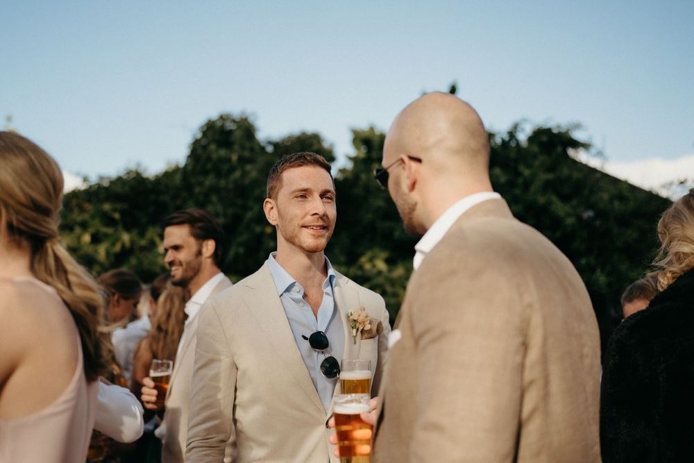 Wedding guests in casual attire enjoying conversation during an outdoor cocktail reception.