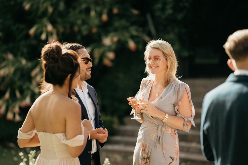 Wedding guests enjoying conversation during outdoor reception in natural setting.
