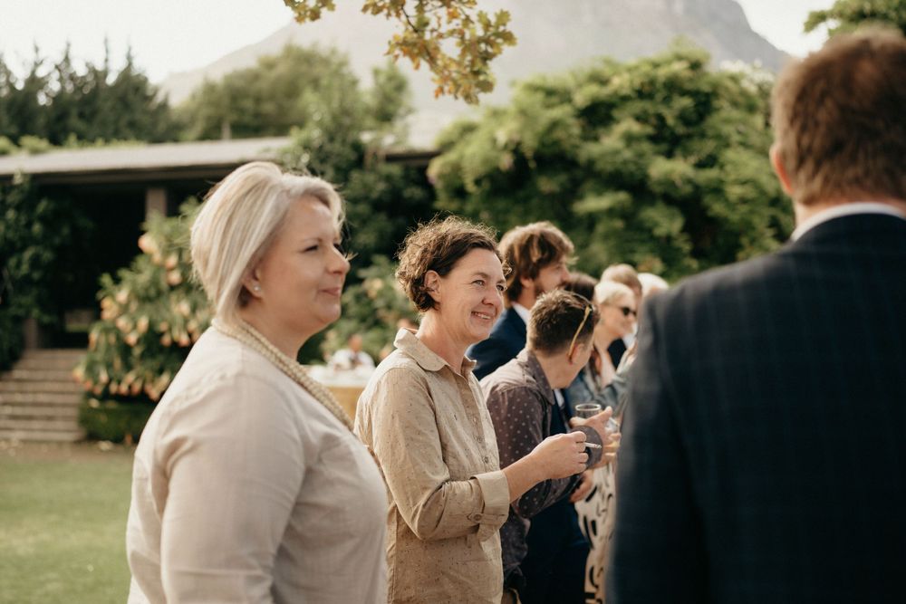 A group of guests enjoying drinks and conversation during an outdoor garden reception.