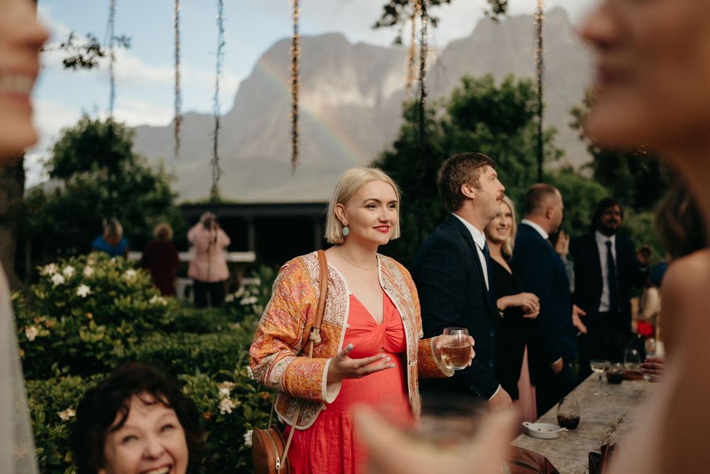 Wedding guests mingling at an outdoor reception with mountain views in the background.