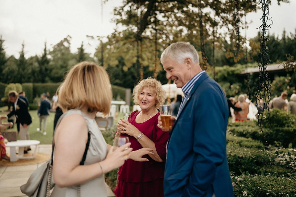 Guests enjoying drinks and conversation at outdoor garden wedding reception.