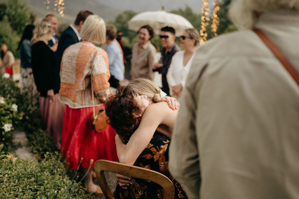 Wedding guests enjoying a casual outdoor celebration with string lights and garden scenery.