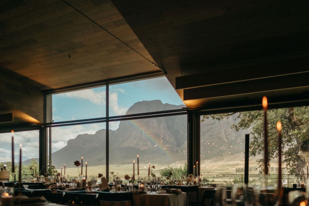 Modern wedding reception venue with panoramic mountain views through floor-to-ceiling windows.