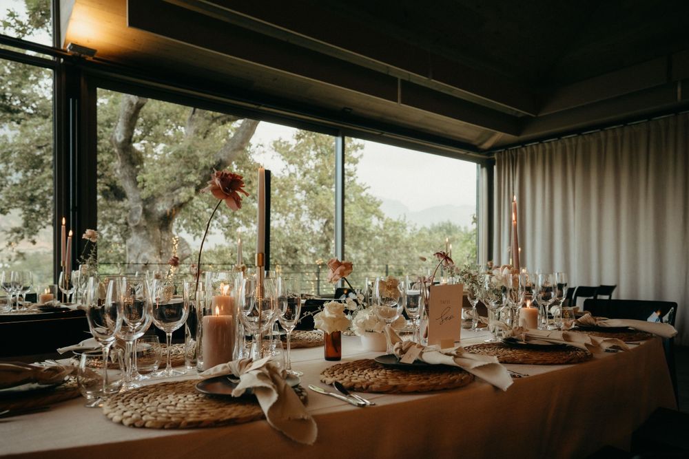 An elegant wedding reception table setting with wine glasses and candlelight in a modern venue.