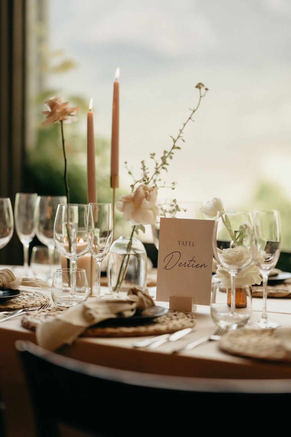 Intimate table setting with candles, place cards and delicate floral arrangements for a wedding reception.