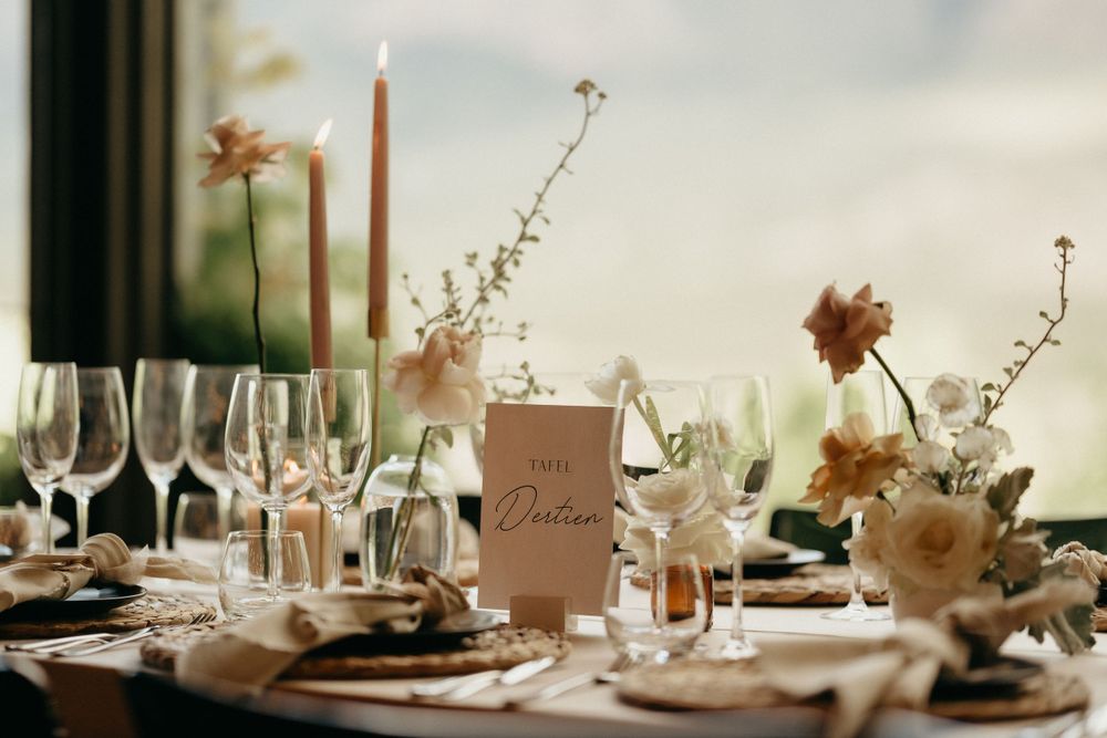 Sophisticated wedding table setting featuring tall candles, floral accents and woven placemats.