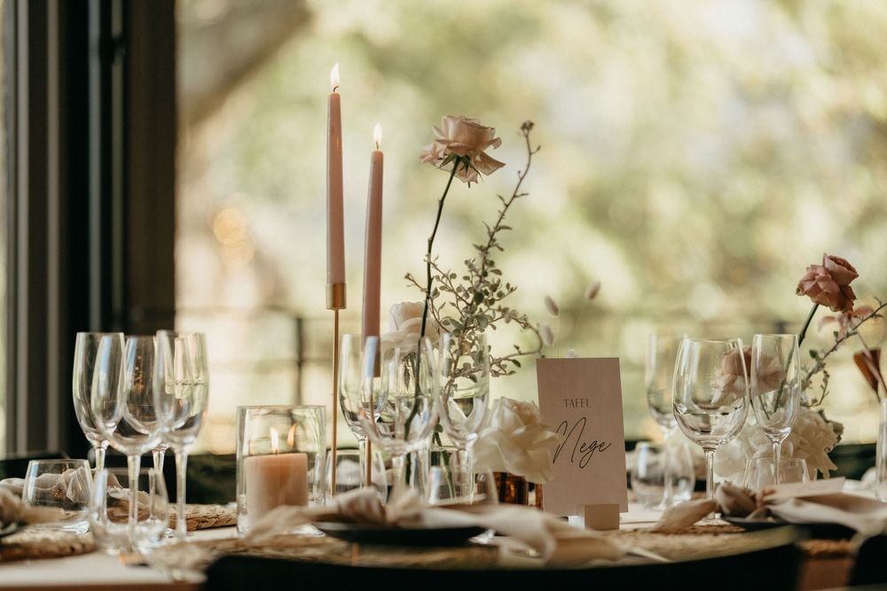 An elegant table setting with wine glasses, candles and delicate floral arrangements in clear vases.