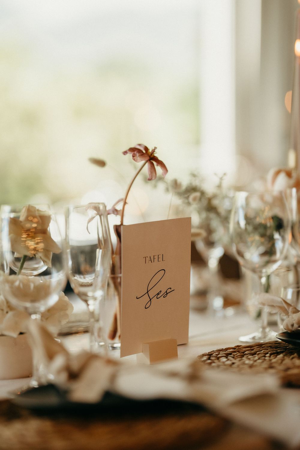 Close-up of minimalist wedding table setting with delicate floral details and place cards.