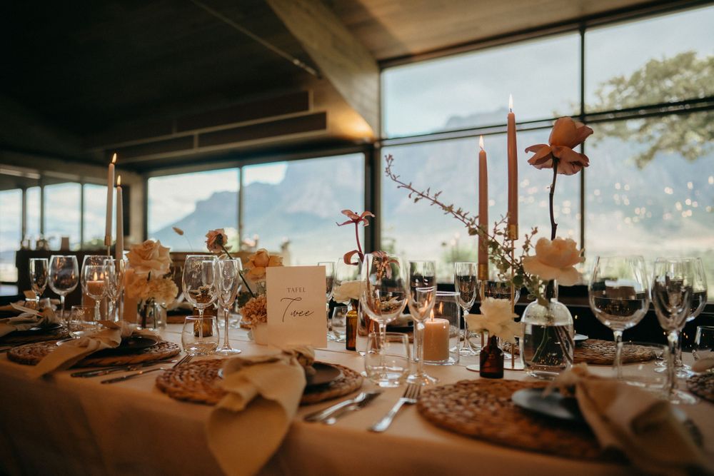 Wedding reception table setup with panoramic mountain views through large windows.