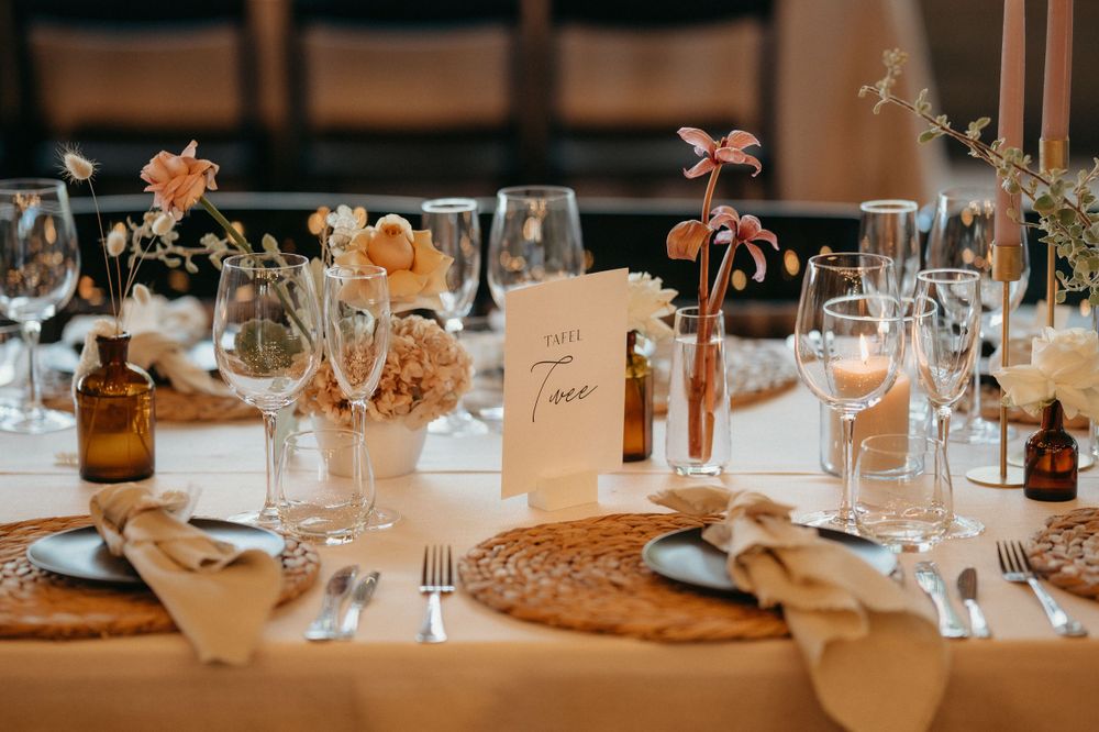 Wedding reception table decorated with peach flowers, taper candles and place settings.