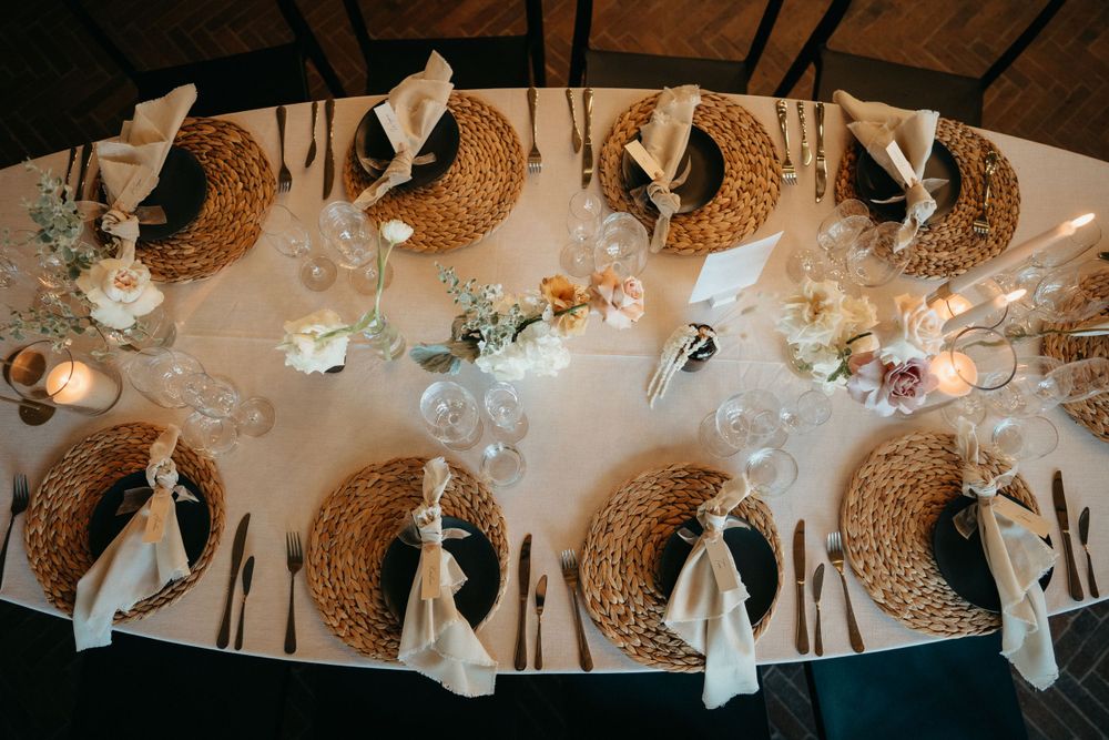 Overhead view of formal table settings with woven chargers and elegant place settings.