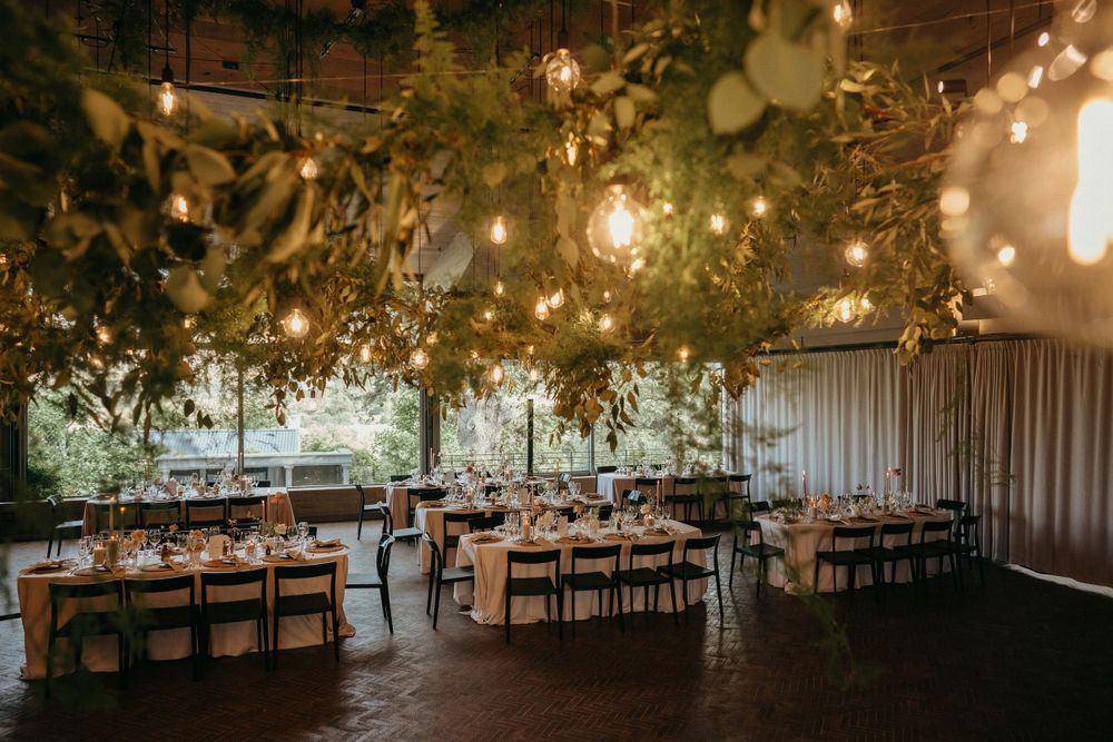 Wedding reception venue with hanging lights and greenery creating a romantic atmosphere.