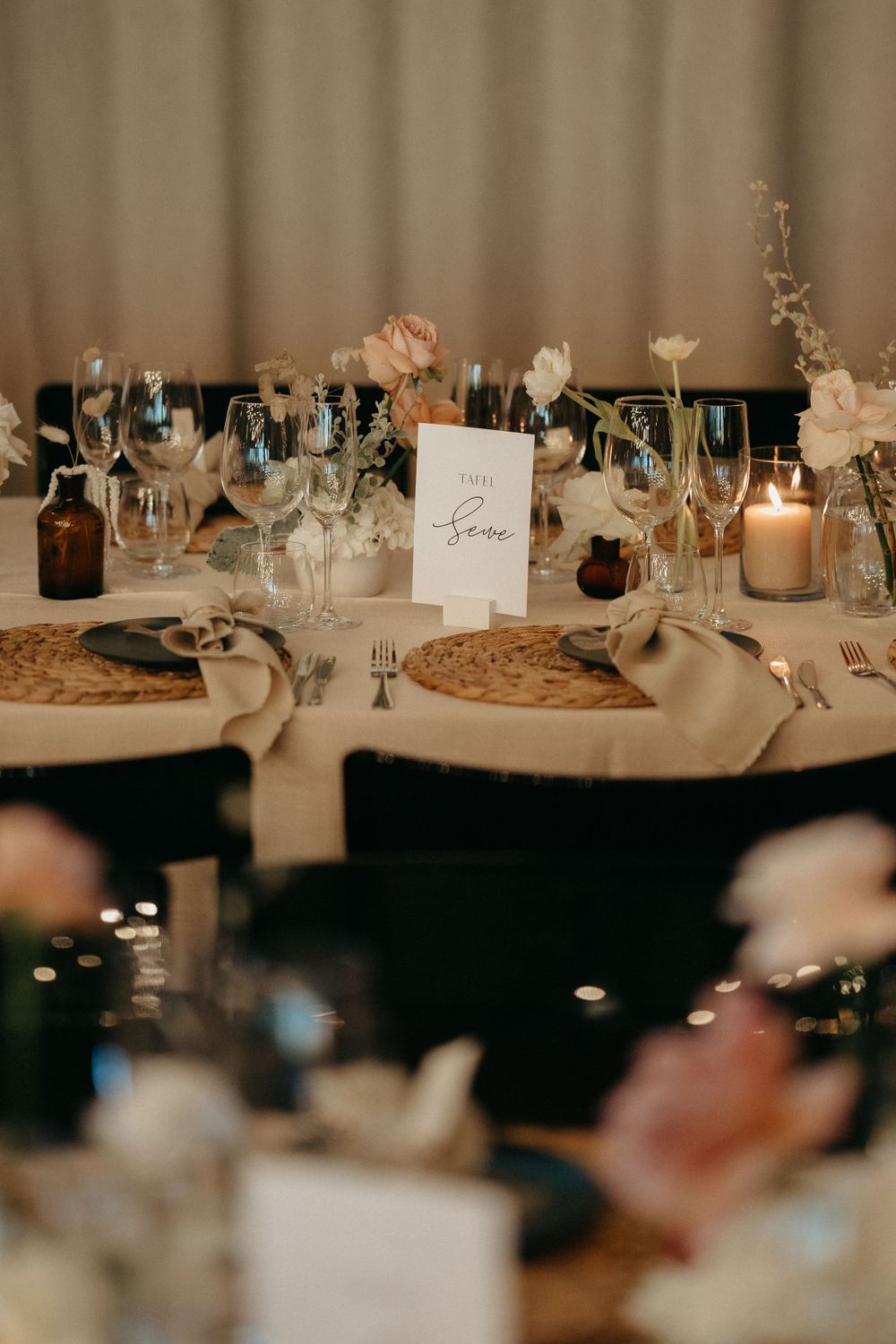 Elegant wedding reception table setting with wine glasses, candles and floral centerpieces.