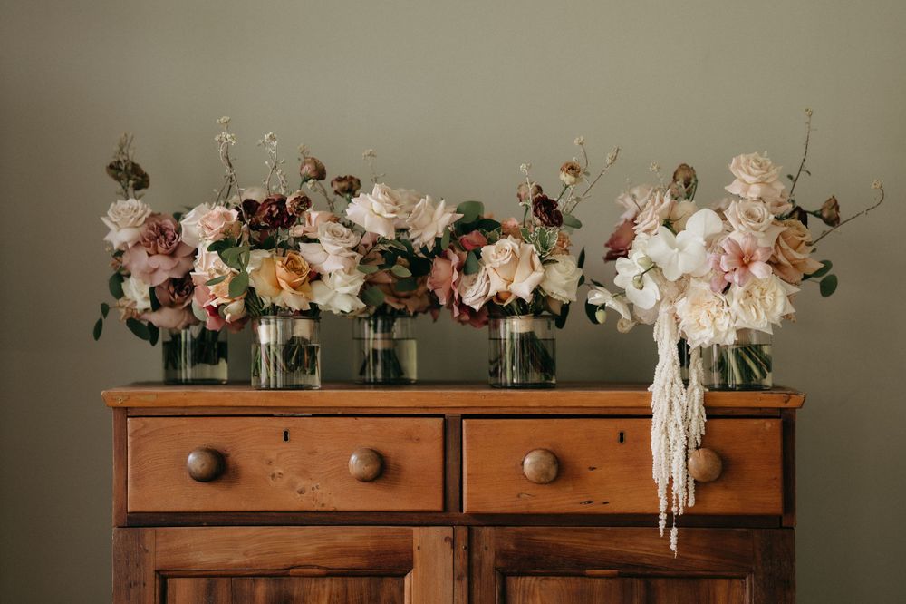 Romantic floral arrangements in glass vases displayed on top of a vintage wooden dresser.