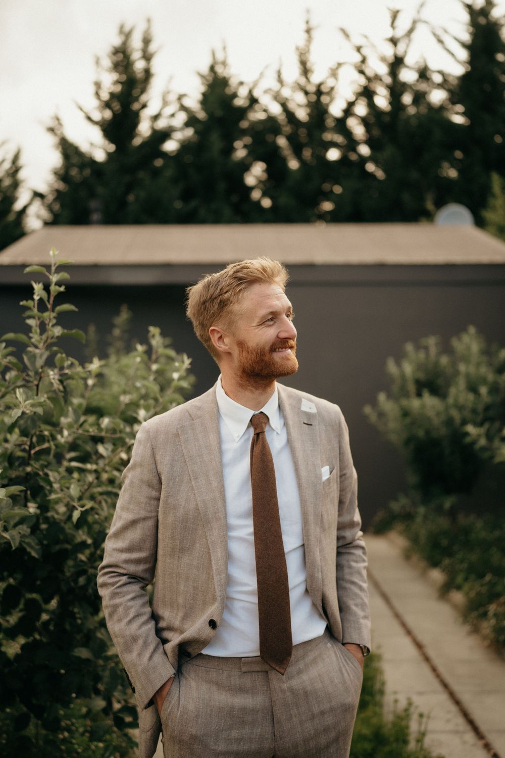 A suited guest smiles while enjoying the outdoor wedding festivities.