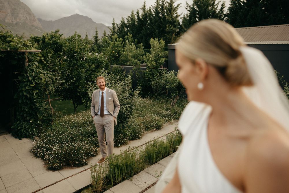 Romantic first look moment in garden setting with mountains in background.