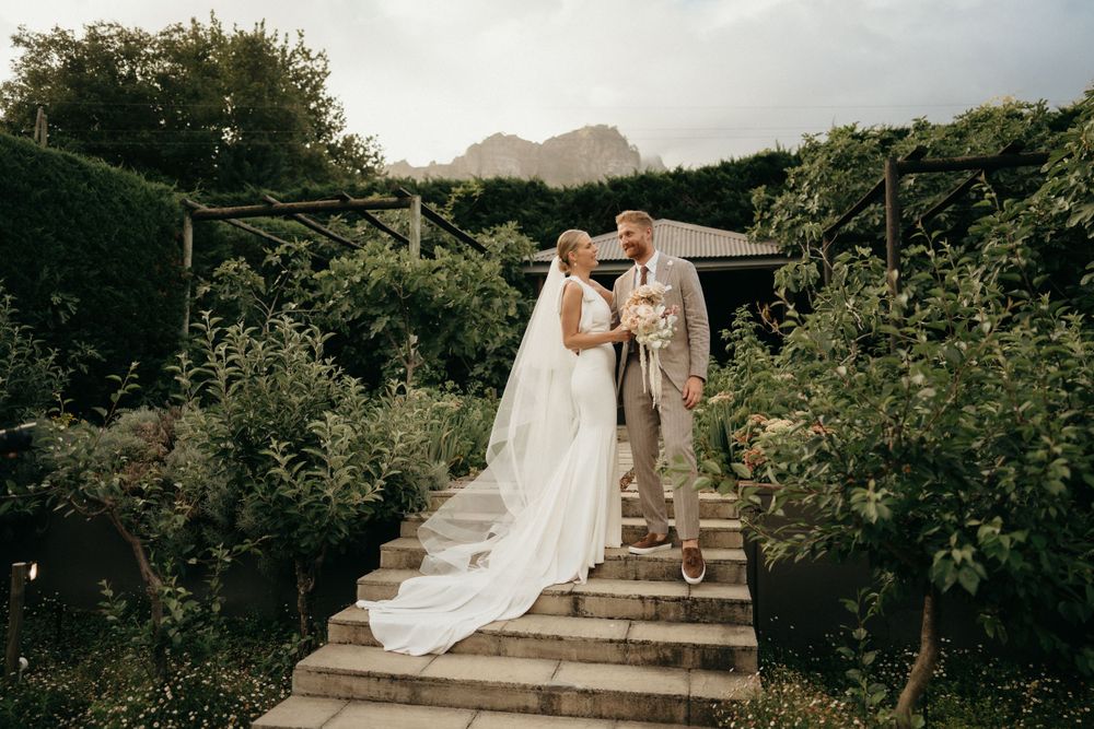 Couple ascending stone garden steps with mountain vista in background.