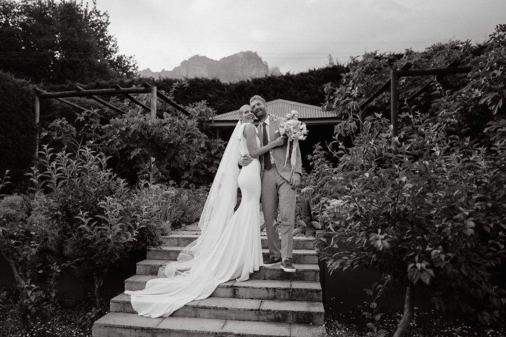 Black and white photo of a couple descending garden steps with mountain views.