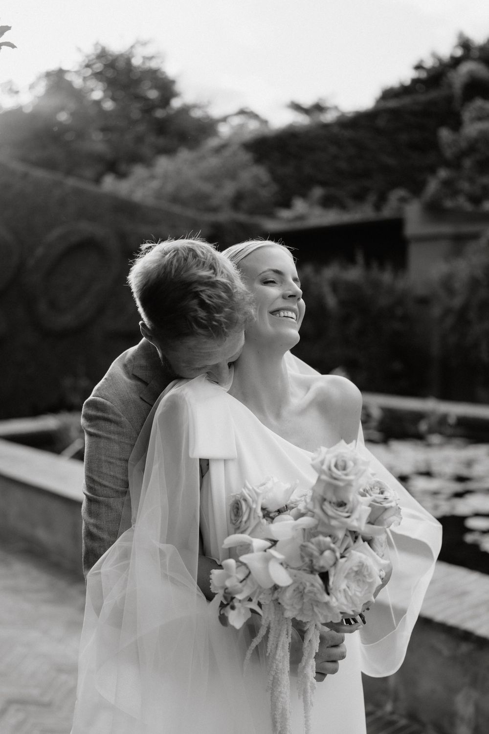 A tender moment captured in black and white as a couple shares an intimate embrace with a beautiful bouquet of roses.