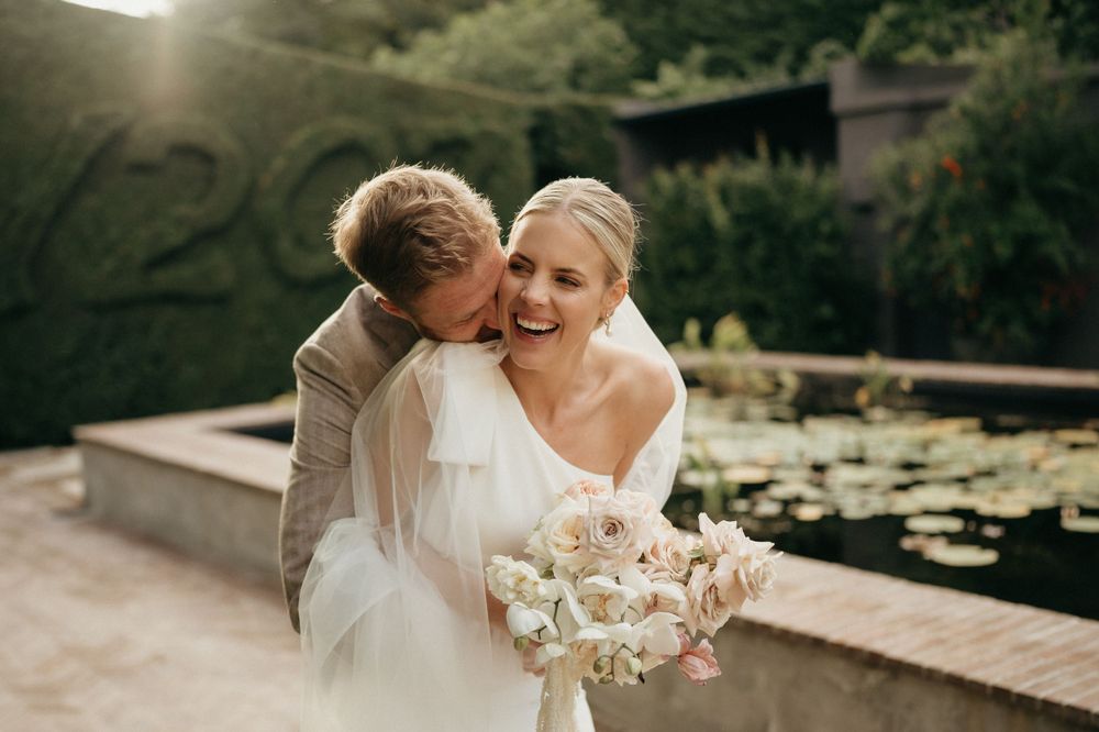 Intimate wedding moment captured by a lily pond with soft natural lighting.
