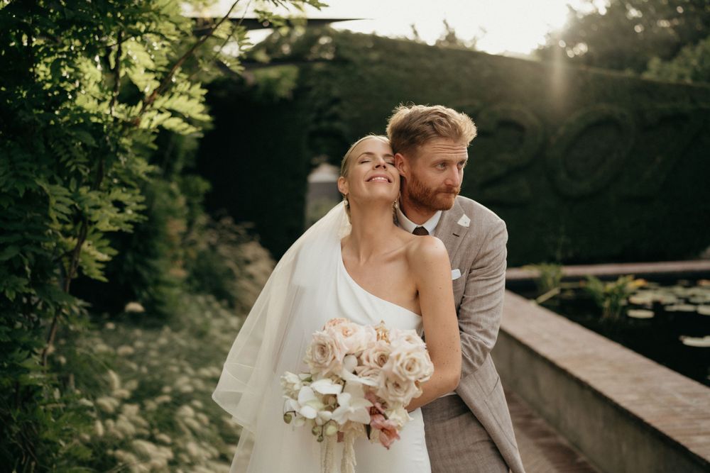 Romantic sunset moment between newlyweds with bride holding white floral bouquet.