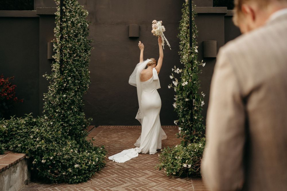 Joyful wedding moment captured showing a couple surrounded by climbing vines on a brick patio.