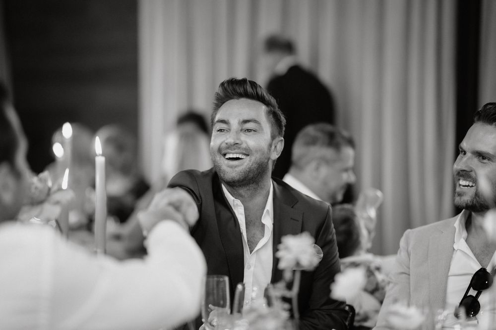 A candid black and white photo at an elegant dinner party with candles on the table and guests enjoying themselves.