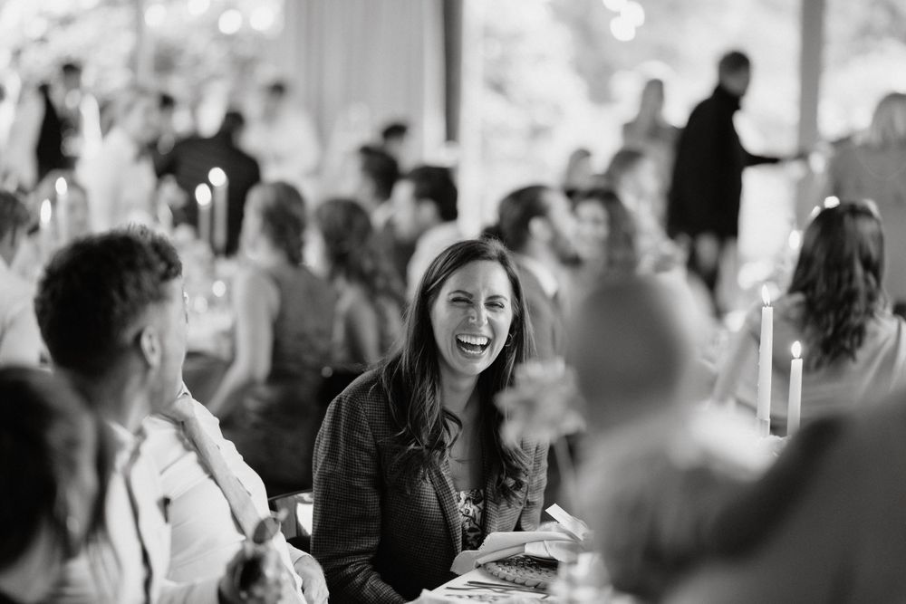 Wedding reception guests enjoying lively conversation at dining tables.