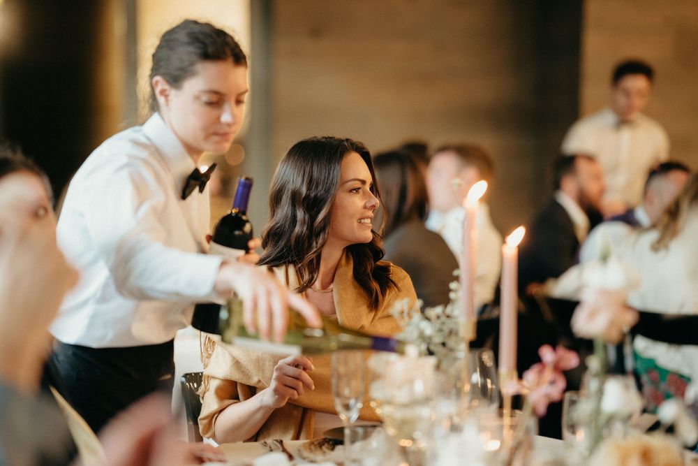 Reception guests enjoying dinner and conversation at elegant indoor venue.
