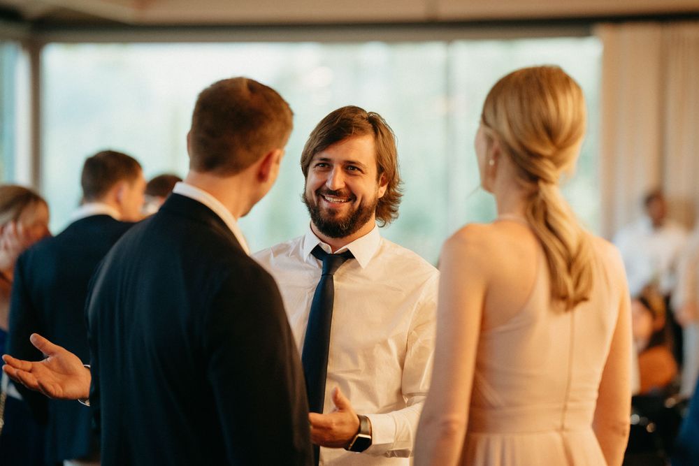 Wedding guests engaging in cheerful conversation during an indoor reception.