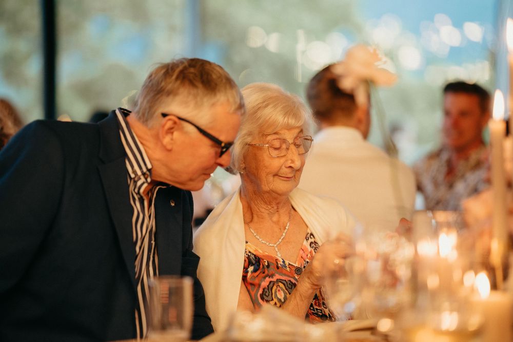 Candlelit reception scene showing guests enjoying conversation at an elegant dinner table.