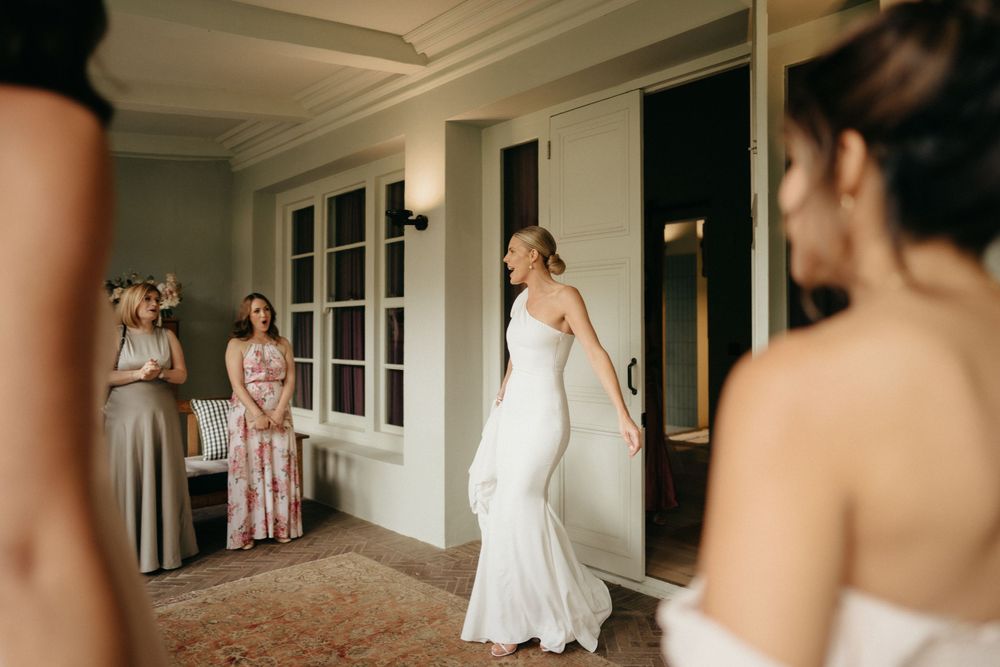 Elegant bridal party watches as the bride twirls in her fitted white wedding gown.