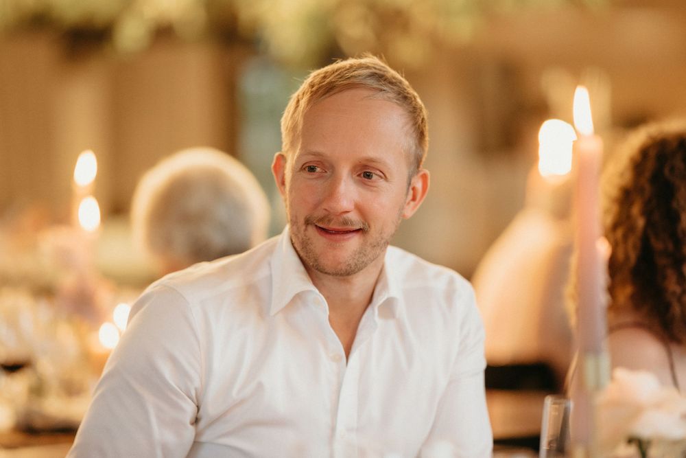 Guest smiling warmly at a candlelit reception dinner.