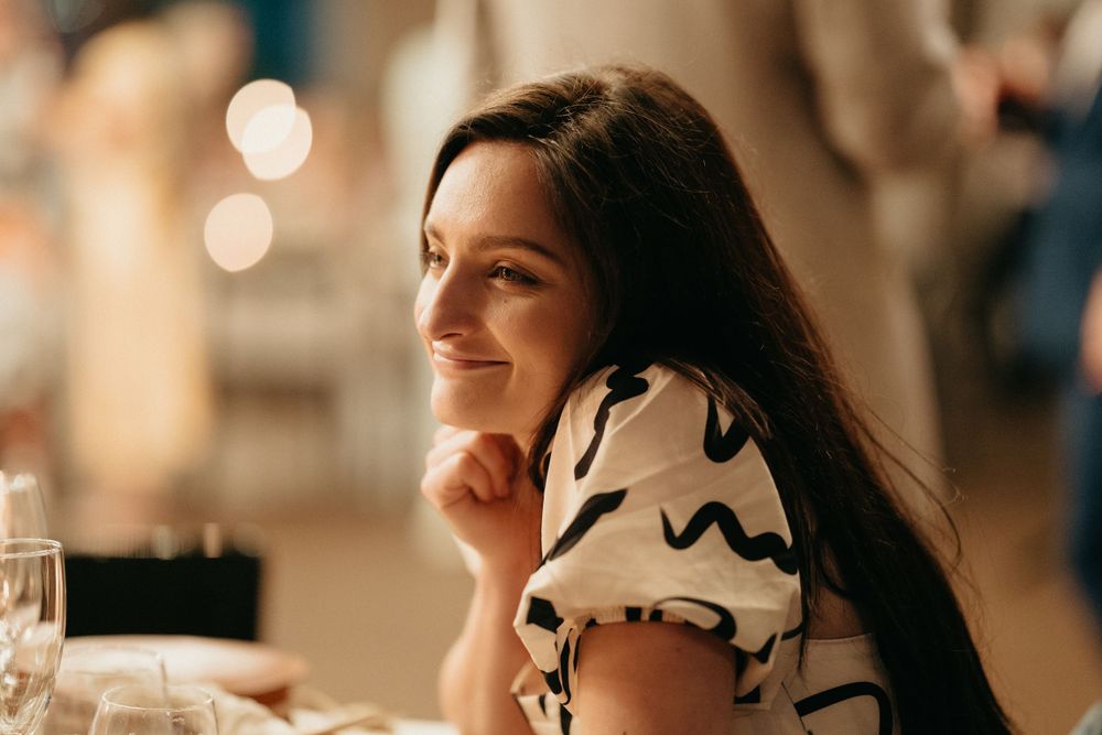A warm candlelit dinner setting with a guest in a patterned dress.