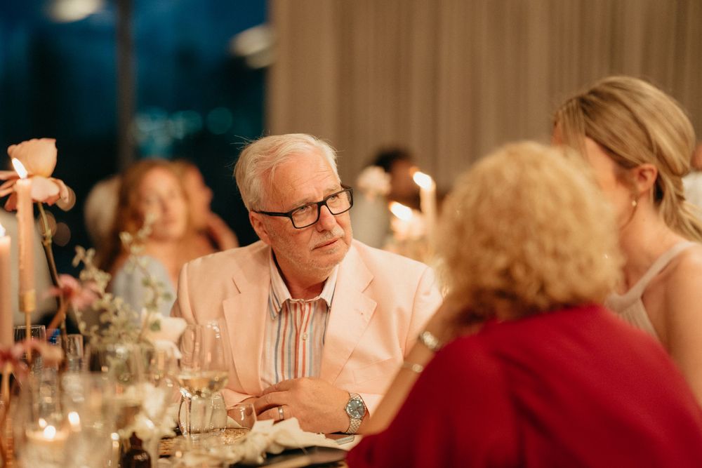 Guests enjoying conversation at an elegant wedding reception dinner table with candlelight ambiance.