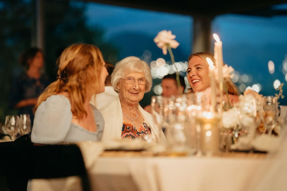 Candlelit wedding reception dinner with guests sharing joyful conversation around the table.