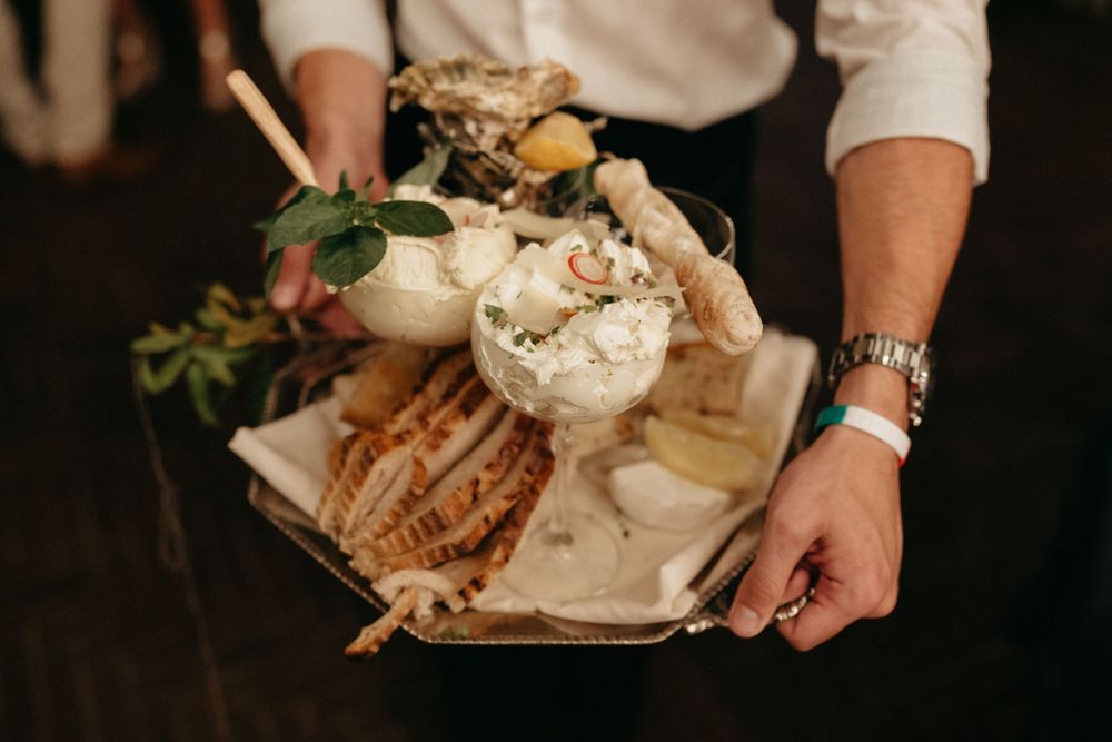 Close up of hands holding a rustic wedding reception appetizer platter with seafood.