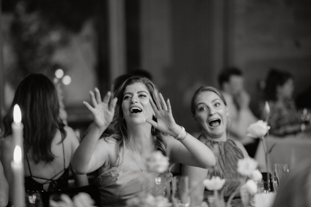 Wedding guests share joyful laughter and reactions during reception celebrations.